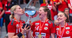 Team Esbjerg genvandt mesterskabet i 2022/2023 og her ses tre glade spillere, hvor Kathrine Heindahl deler et kys med pokalen.