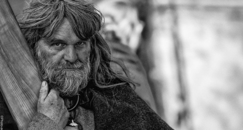 Sort hvid fotografering af en viking fra Ribe Vikinge center, hvor han stod under teltet og solen lyste gennem teltet